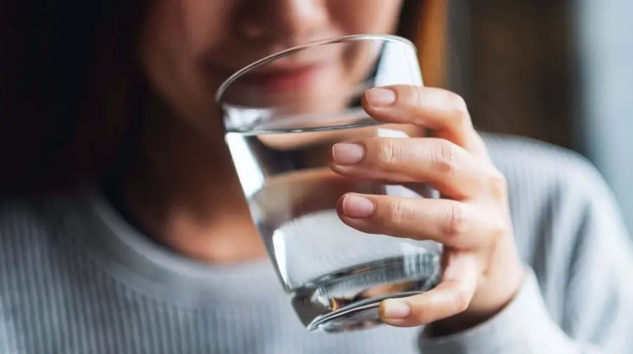 Happy customer enjoying a glass of pure, crystal-clear Reverse Osmosis (RO) drinking water from United Water Softeners’ PureGuard system in Houston.