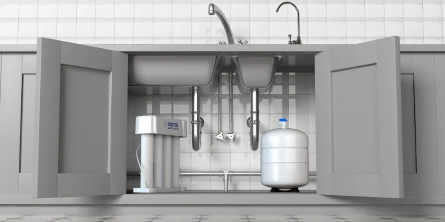 Clean professional installation of a United Water Softeners under-sink reverse osmosis drinking water system with dedicated storage tank, neatly tucked inside open gray kitchen cabinets under a double sink – premium pure water delivered by Houston’s best water company