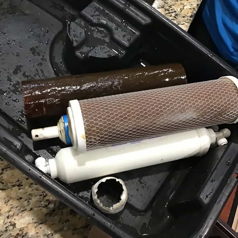 Spent water filter cartridges next to a clean replacement during a filtration system service