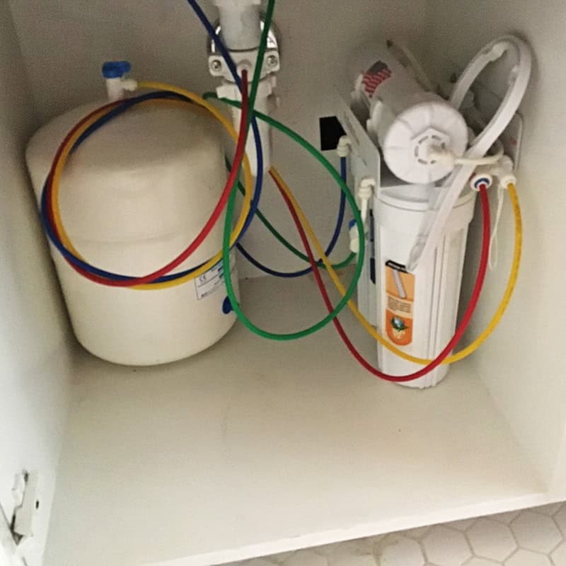 Reverse osmosis system under a kitchen sink being serviced