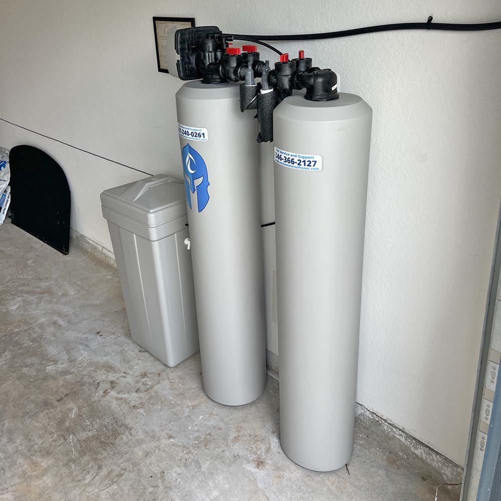 Elite Package whole-house water softener and carbon filtration system professionally installed inside the garage in Conroe, Texas by United Water Softeners – Houston’s #1 rated water company. Certificate of installation visible.