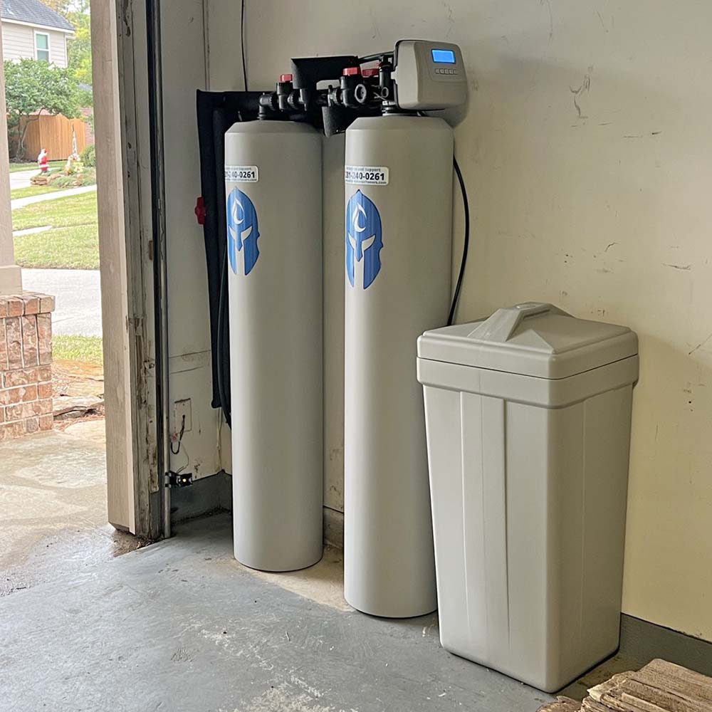 Elite Package whole-house water softener and carbon filtration system professionally installed in the corner of a garage in Cypress, Texas by United Water Softeners – Houston’s #1 rated water company.