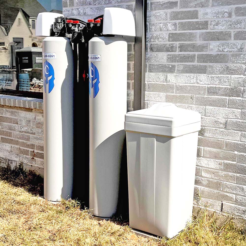 Elite Package whole-house water softener system with smart motherboard professionally installed outside a home in the Katy area by United Water Softeners – Houston’s #1 rated water company.