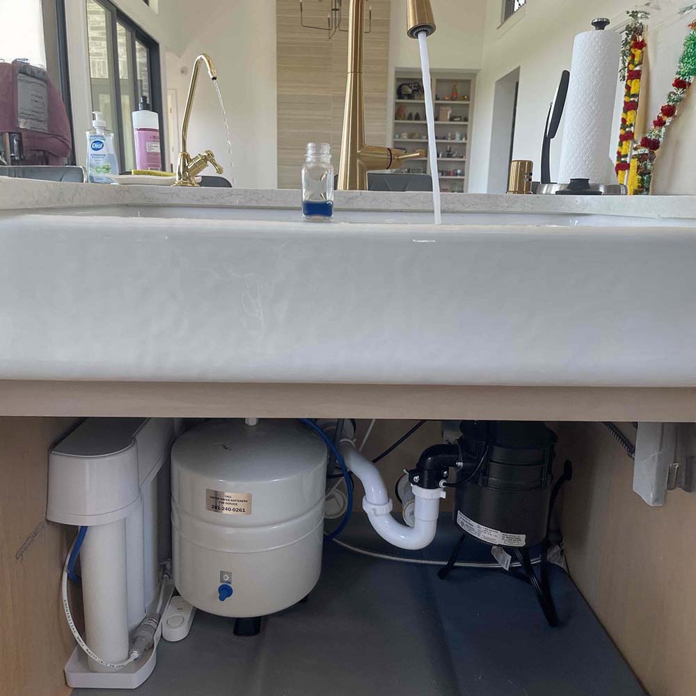Premium reverse osmosis (RO) drinking water system with custom gold faucet and smart leak detector professionally installed under the kitchen sink in Katy, Texas by United Water Softeners – Houston’s #1 rated water company.