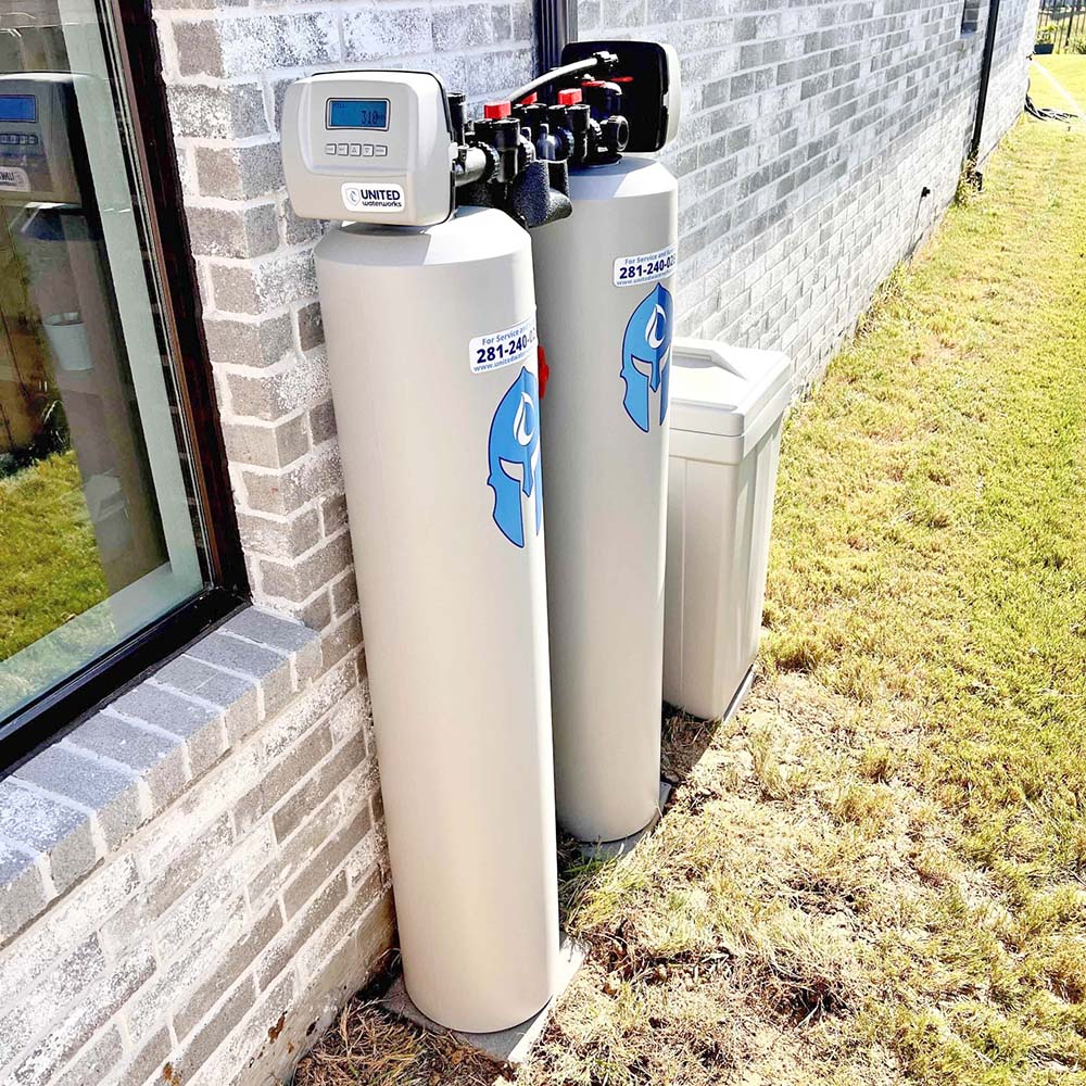 Elite Package whole-house water softener system with smart motherboard professionally installed outside a home in the Katy area by United Water Softeners – Houston’s #1 rated water company.