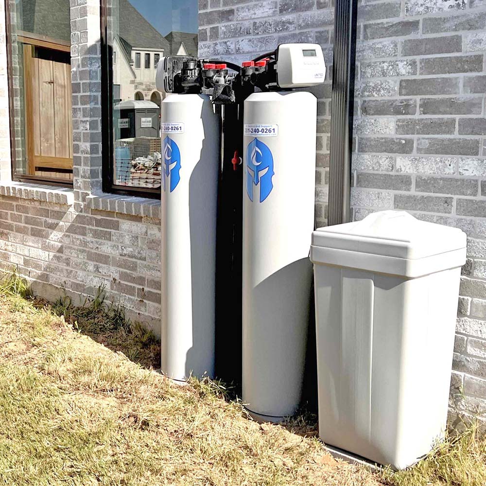 Elite Package whole-house water softener system with smart motherboard professionally installed outside a home in the Katy area by United Water Softeners – Houston’s #1 rated water company.