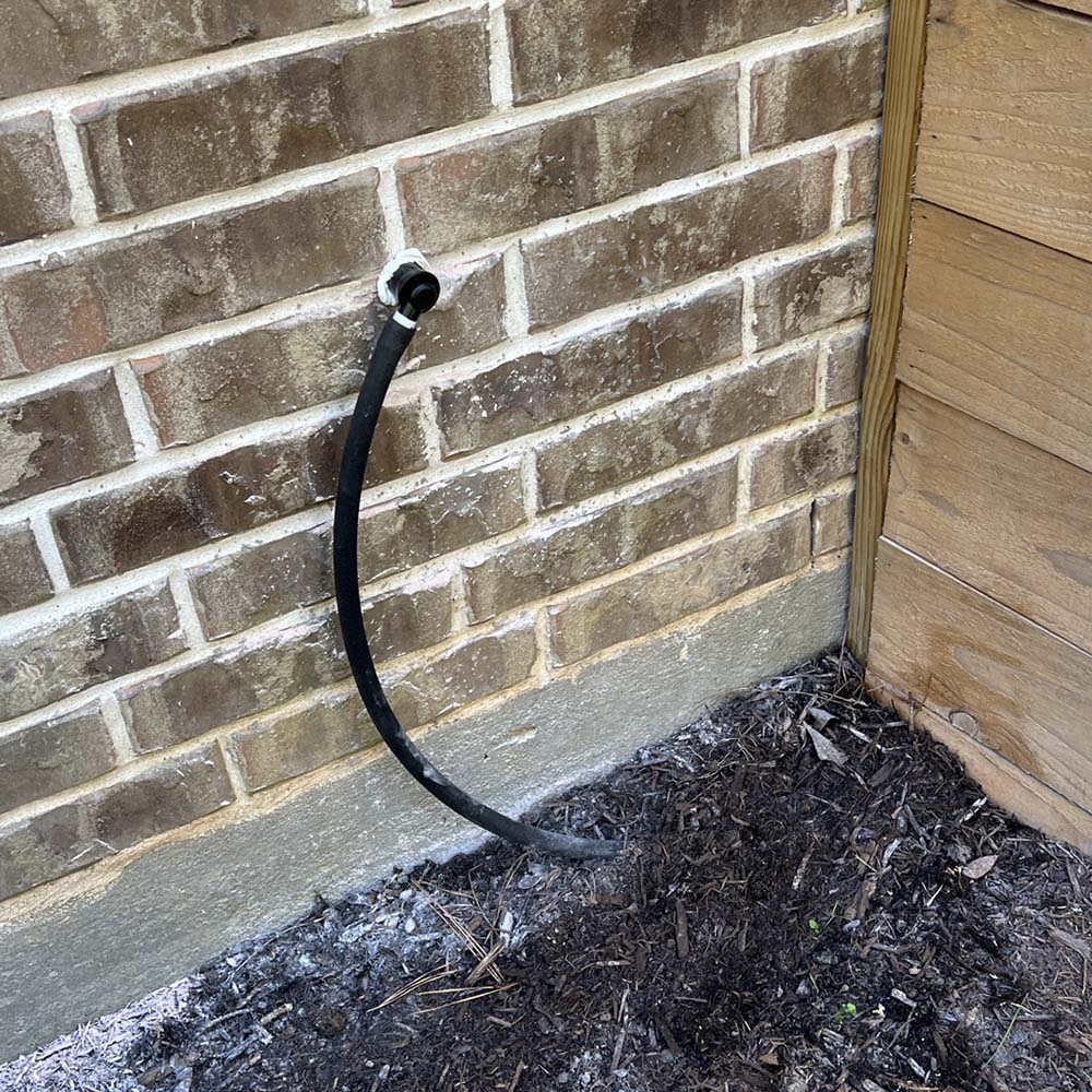 Professional water softener drain line neatly exiting through the brick wall on a home in Richmond, Texas – expertly installed by United Water Softeners.